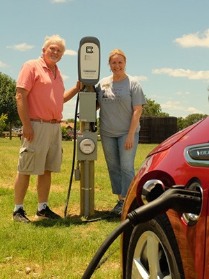 Smiling couple charging their red chevy volt with a ClipperCreek EV Charging Station in Fredericksburg Texas Torre di Pietra